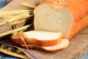 Wall Mural - fresh sliced bread isolated with wheat ears on jute cloth,top view 