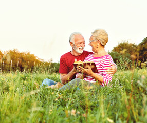 Wall Mural - woman man outdoor senior couple happy lifestyle retirement together smiling love reading nature book