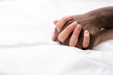 Hands close up multiracial couple african man and caucasian woman romantically touch each other on bed, lovers making Passion love