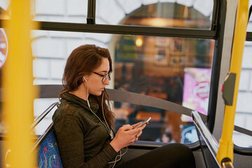 Poster - She takes the bus everywhere. High angle shot of an attractive young woman listening to music while sitting on a bus.