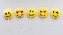 A Row Of Smiley Face Merengue Cookies On Lollipop Sticks.