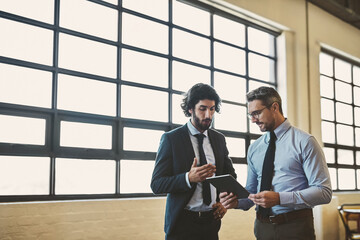 I think youre off to a good start. Shot of two well-dressed businessmen brainstorming together over a tablet in their office.