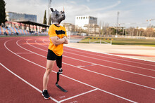 Amputated Man Wearing Rhinoceros Face Mask Standing With Arms Crossed On Running Track
