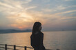 © peach100 - 夕暮れの海沿いで散策する女性