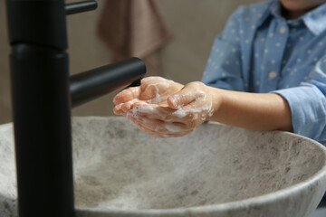 Wall Mural - Little girl washing hands with liquid soap in bathroom, closeup