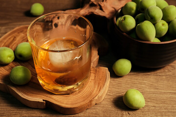 Homemade plum wine or UMESHU and green plums on wooden plate.