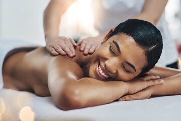 Wall Mural - That feels amazing. Shot of a relaxed an cheerful young woman getting a massage indoors at a spa.