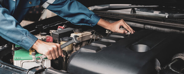 Car mechanic working on car engine, car maintenance concept.