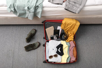 Sticker - Open suitcase with clothes, accessories and shoes on floor near bed indoors, flat lay