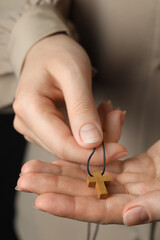 Woman holding wooden Christian cross, closeup view