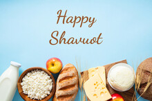 Happy Shavuot Concept. Dairy Products, Bread, Fruits, Wheat On Blue Background. Jewish Holiday Eating.