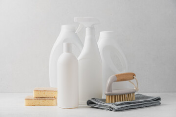 White bottles with cleaning liquids, sponge rag and brush on white background. Cleaning service concept