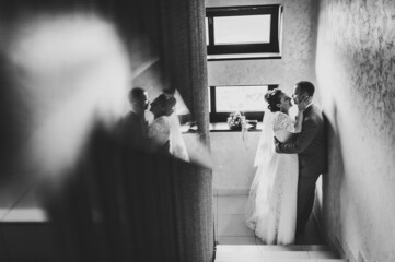 The bride and groom near window. First meeting. Newlyweds hugging indoors. Happy wedding day of marriage. Black and white photo.