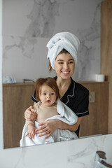 young mother with baby in towels after shower in bathroom. concept of hygiene and cleanliness.