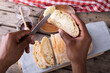 Close-up of african american man cropped hands applying butter on bread slice