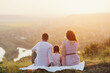 Family sitting on the hill and enjoy beautiful landscape and sunset or sunrise. Travel family concept.