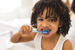 © WavebreakMediaMicro - Portrait of hispanic curly haired boy brushing teeth in bathroom at home