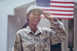 Leinwandbild Motiv Happy female mid adult african american soldier in uniform standing outside house