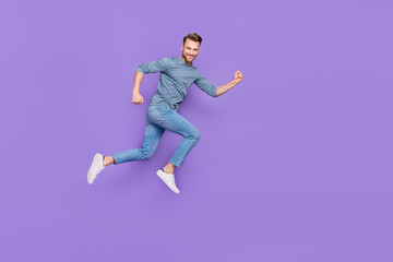 Poster - Photo of excited attractive guy wear grey shirt running fast jumping high empty space isolated violet color background