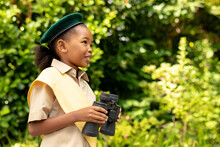Smiling African American Scout Girl In Uniform Holding Binoculars In Forest