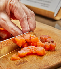 Wall Mural - Chef cuts the salmon into cubes with knife to prepare the dish according to the recipe