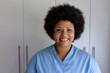 © wavebreak3 - Portrait of smiling african american mid adult female nurse standing against cabinet in hospital