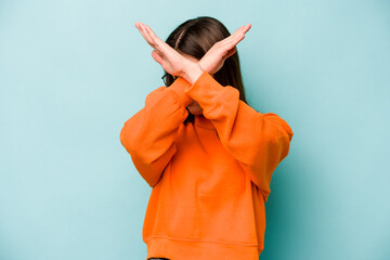 Young caucasian woman isolated on blue background keeping two arms crossed, denial concept.