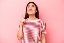 Young Caucasian Woman Isolated On Pink Background Indicates With Both Fore Fingers Up Showing A Blank Space.