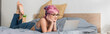 © LIGHTFIELD STUDIOS - barefoot woman with dyed hair lying on bed and watching movie on laptop, banner.