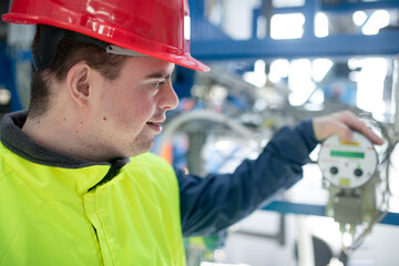 Wall Mural - Young man with Down syndrome working in industrial factory, social integration concept.