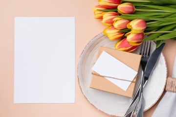 Wall Mural - Mockup menu card. Top view of table setting with menu card, present, cutlery and fresh tulips for festive dinner.