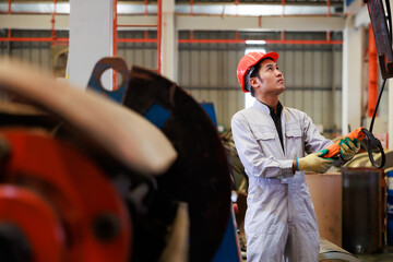 Close up worker hands control indoor overhead crane to lift up metal construction object on metal sheet factory.