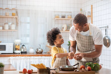 Happy Black African American Father And Little Son Cooking Together In Kitchen. Brazilian Single Dad And Afro Boy With Smiling Face.