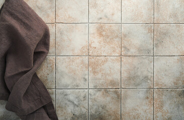 Wall Mural - Linen kitchen brawn towel napkin on old ceramic tile table background. Cooking stone backdrop. Top view with copy space. Flat lay