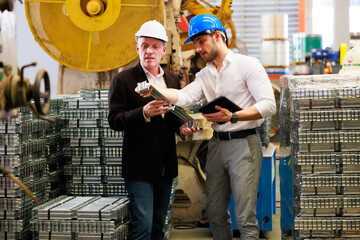 Wall Mural - lathe and stamping metal machine. Caucasian business man and Factory engineer in hard hat helmet talking and discussion at Heavy Industry Manufacturing Factory.