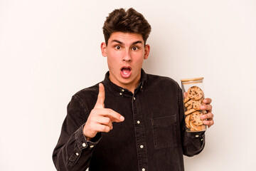 Young caucasian man holding cookies jar isolated on white background having an idea, inspiration concept.