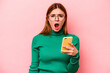 Young caucasian woman holding mobile phone isolated on pink background screaming very angry and aggressive.