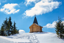 A Group Of Hikers Standing Near A Romanian Wooden Chalet On The Top Of A Snowy Hill