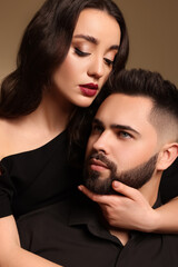 Wall Mural - Handsome bearded man with sexy lady on brown background, closeup