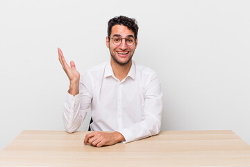 Wall Mural - hispanic handsome man feeling happy, surprised realizing a solution or idea. businessman and desk concept