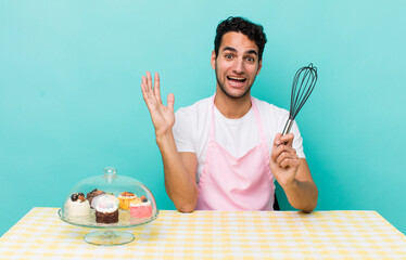 Wall Mural - hispanic handsome man feeling happy and astonished at something unbelievable. home made cakes cocnept