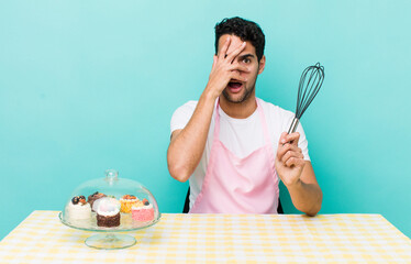 Wall Mural - hispanic handsome man looking shocked, scared or terrified, covering face with hand. home made cakes cocnept