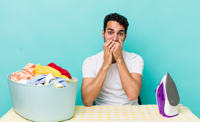 hispanic handsome man covering mouth with hands with a shocked iron and clothes concept