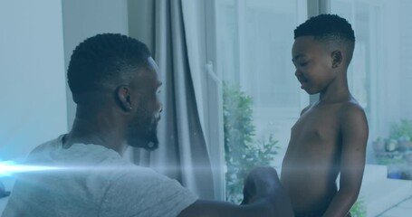 Canvas Print - Animation of lights over happy african american father and son undressing and clapping hands