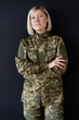 © LIGHTFIELD STUDIOS - blonde military woman standing with crossed arms and looking at camera isolated on black.