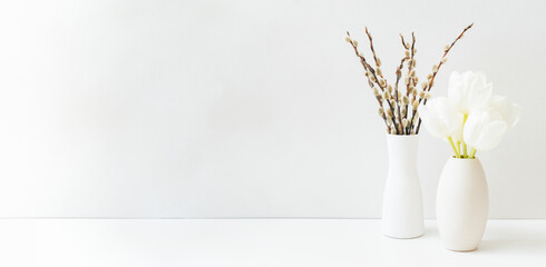 Wall Mural - White spring tulips in a vase and willow branch on a white table. Mock up for displaying works