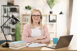 © sofiko14 - Professional mature Caucasian woman reading financial charts while presenting colleagues through video call on laptop. Female freelancer or manager sitting at workplace and looking at the camera.