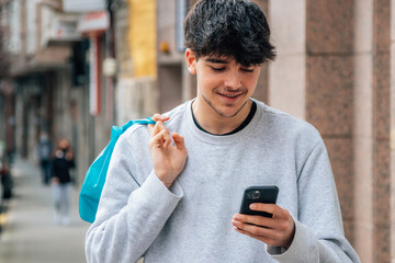 Wall Mural - young man in the street with shopping bag and mobile phone