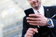 © Monstar Studio - Close up of young stylish tide up businessman in formal suit use modern smartphone. Successful male trader employer manage plan tasks with cellphone wearing hand watch. Job time management concept.
