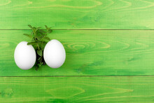 Two White Eggs On A Green Wooden Background.Easter Background.Postcard With Space For Text.